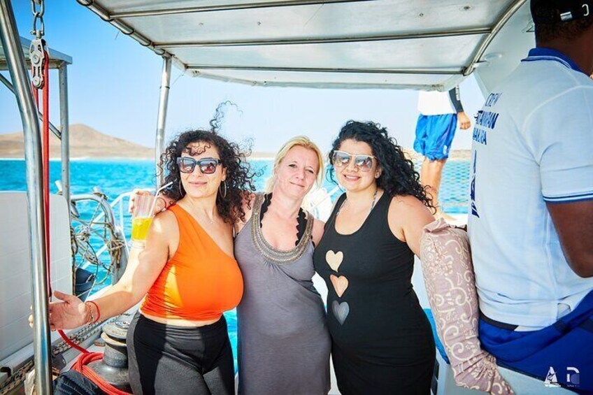 Drei Personen in einem Boot, mit blauem Meer und Land in der Ferne. 5