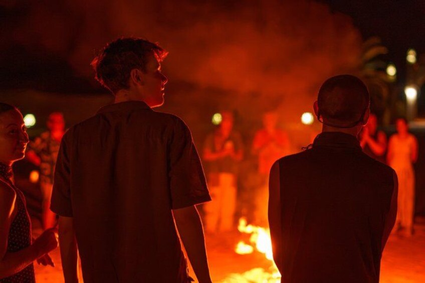 A group of people standing in a dimly lit area with a fire in the background. 3
