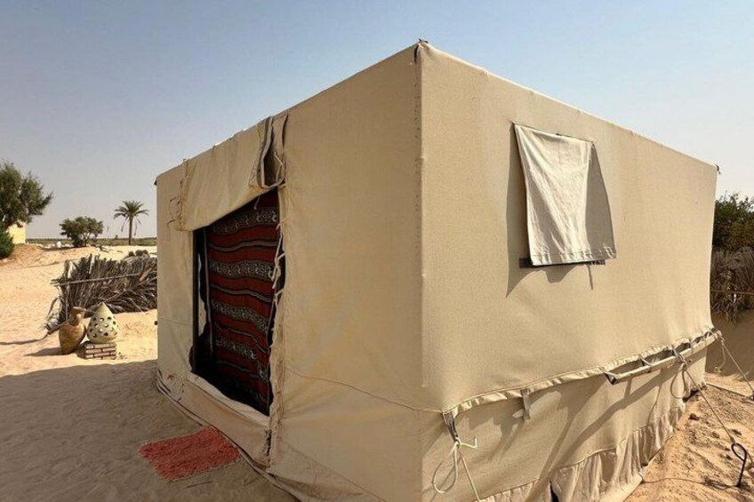A beige tent with a partially open door, set in a desert with sparse vegetation. 4