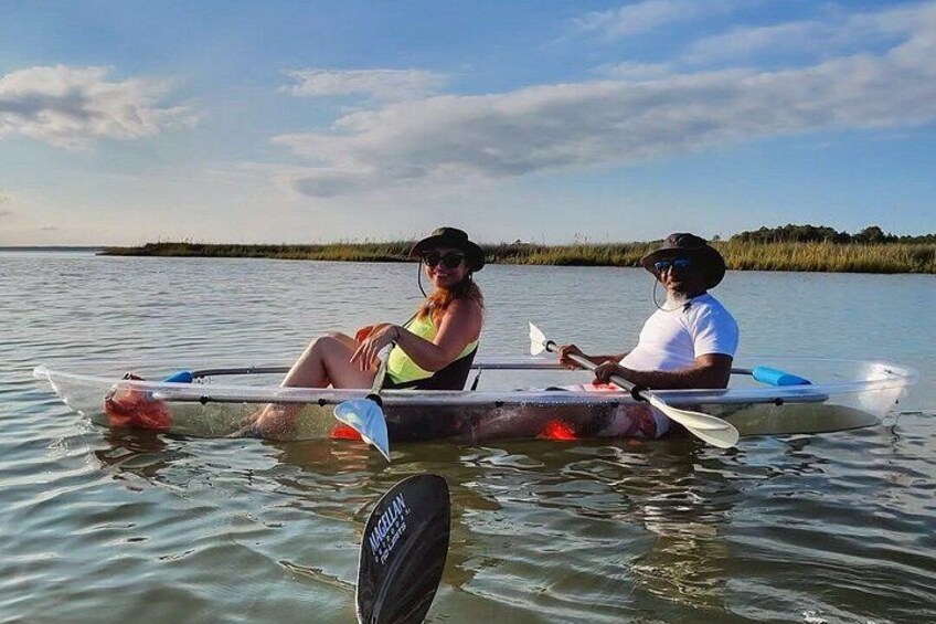 Two people in a kayak on a calm body of water with a distant shoreline. 3