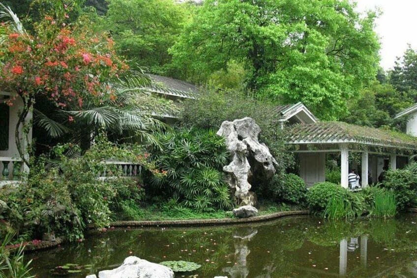 A garden with a pond, a rock formation, and traditional architecture. 5