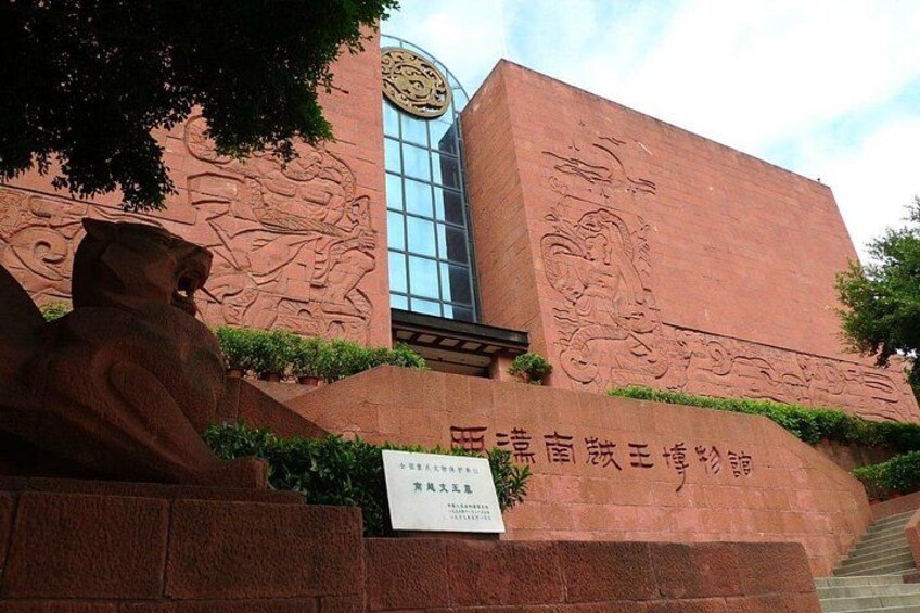 A building with red brick walls and a large statue of a lion. There is a sign with Chinese characters and a staircase leading up to the entrance. 3