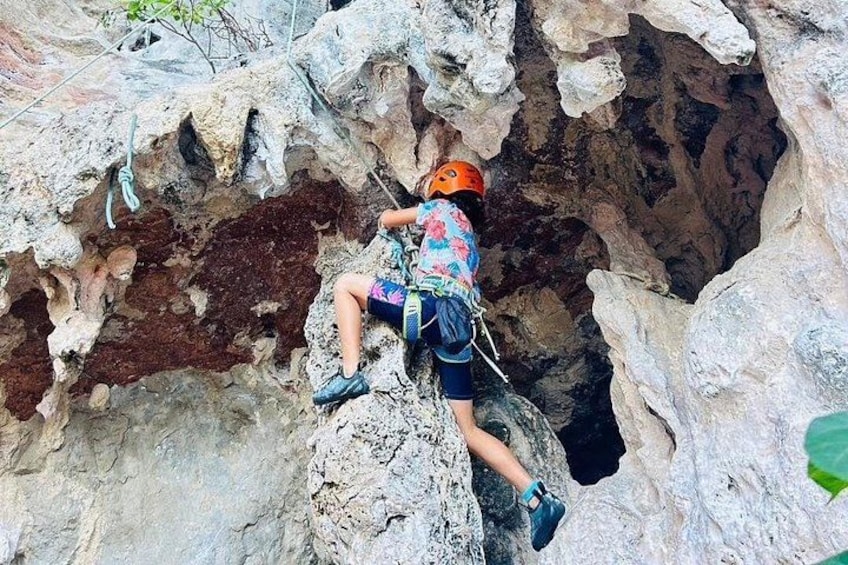 Une personne escalade une falaise rocheuse, portant un casque et un harnais. 3