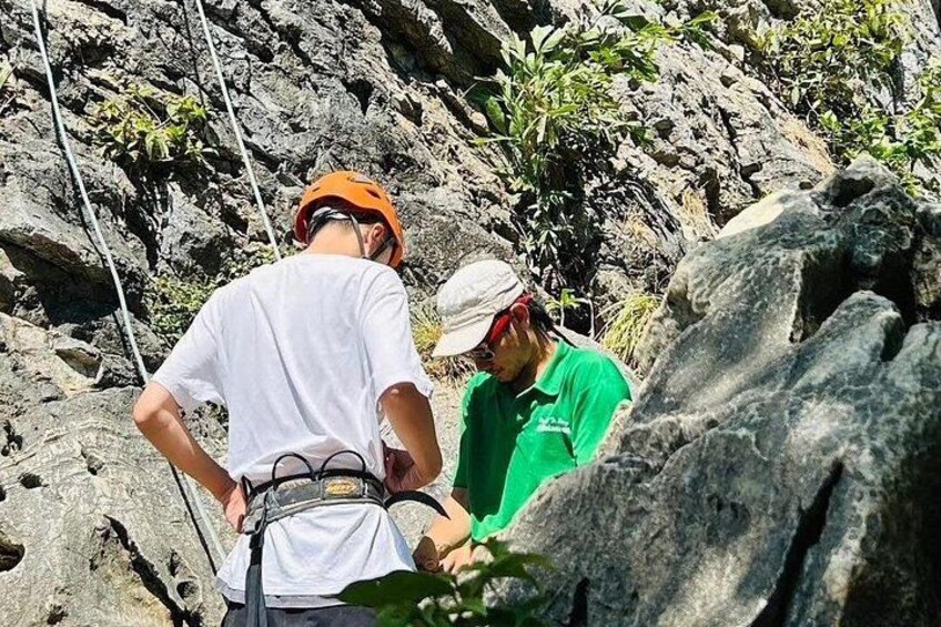 Deux personnes, vêtues d’équipements adaptés aux activités de plein air, se trouvent près d’un terrain rocheux : l’une porte une chemise blanche et un casque orange, l’autre une chemise verte et un casque blanc. 2