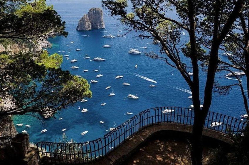 Vista sulla costa con imbarcazioni, un promontorio roccioso e un ponte. 2