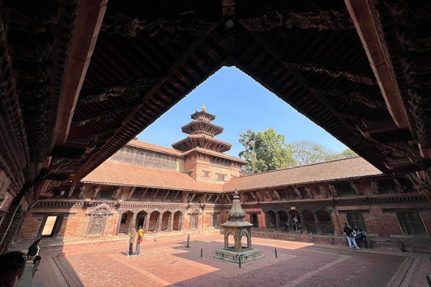 Un patio con una construcción de estilo pagoda, una fuente central y una persona caminando. 3