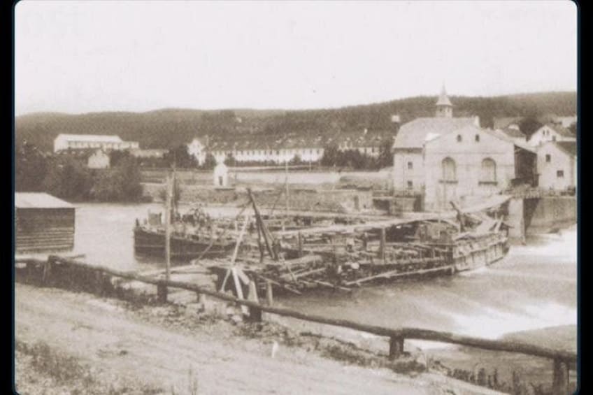 A river with a dock, a large building with a tower, and a bridge in the background. 2