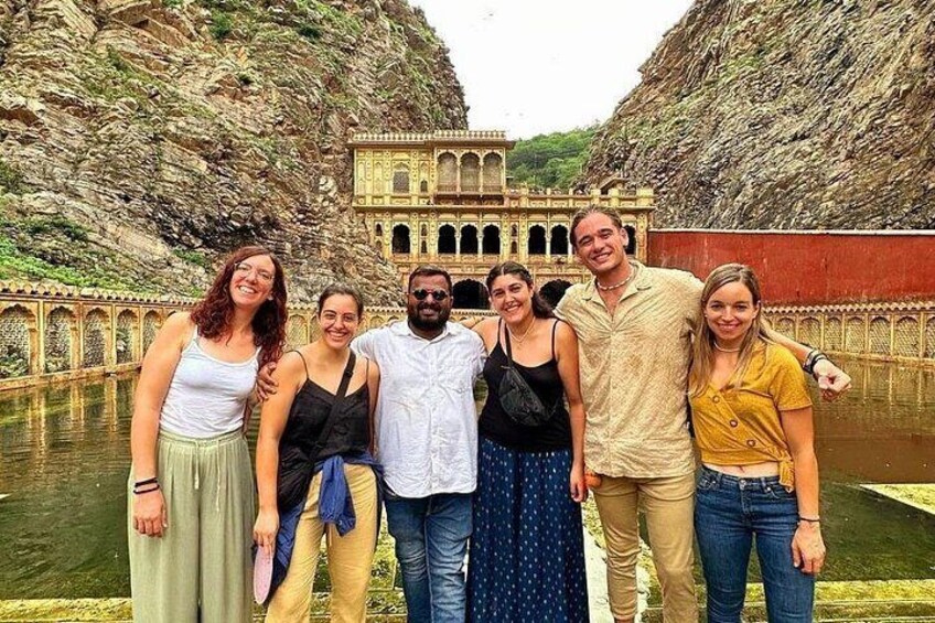 A group of people standing in front of a historic building with a water body behind them. 5