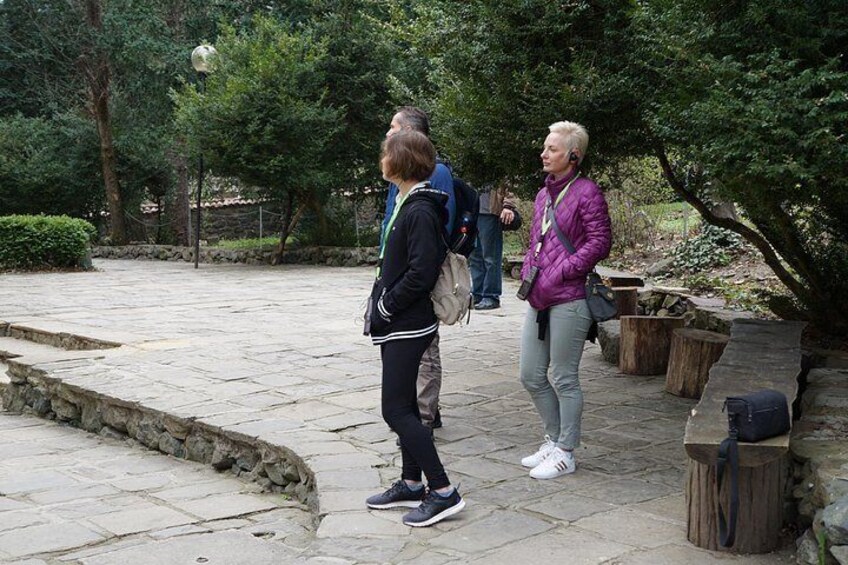 Two people standing on a stone pathway in a park with trees and wooden benches. 5