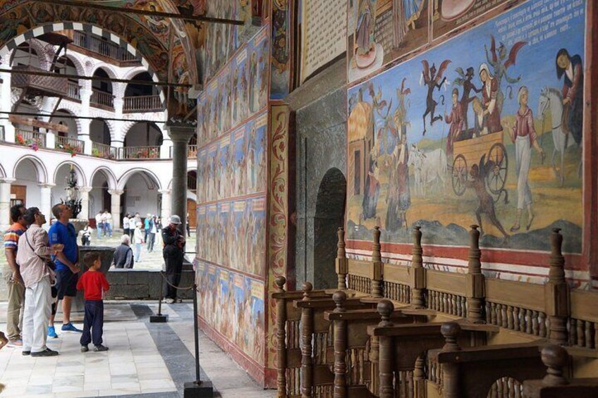 An interior courtyard with a mural, columns, and a fountain. 4