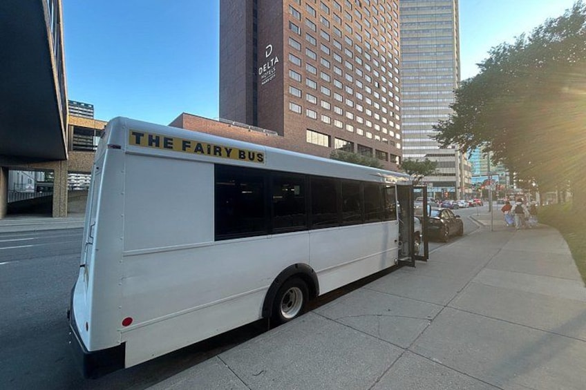 A white bus with 'THE FAIRY BUS' written on the side parked on a sidewalk. 5