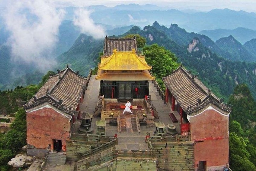 A traditional Chinese temple with a yellow roof, surrounded by lush green mountains. 3