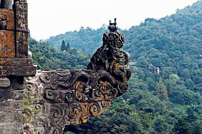 A stone structure with intricate carvings and a lion figure, set against a lush green forest backdrop. 5
