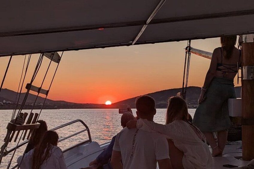 Ein Sonnenuntergang über dem Wasser mit einem Boot und Personen auf dem Deck. 2