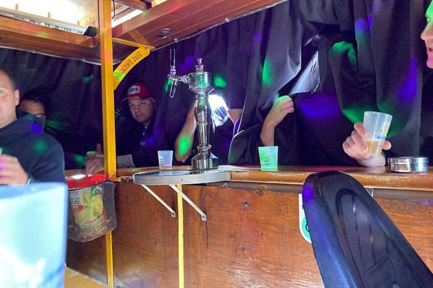A bar with a tap and people holding plastic cups. 3