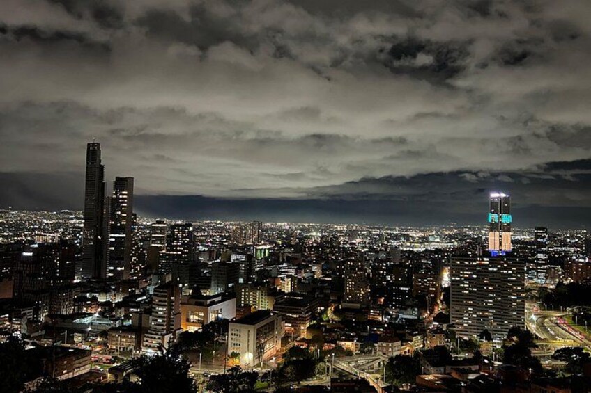 A nighttime cityscape with illuminated buildings and a cloudy sky. 5