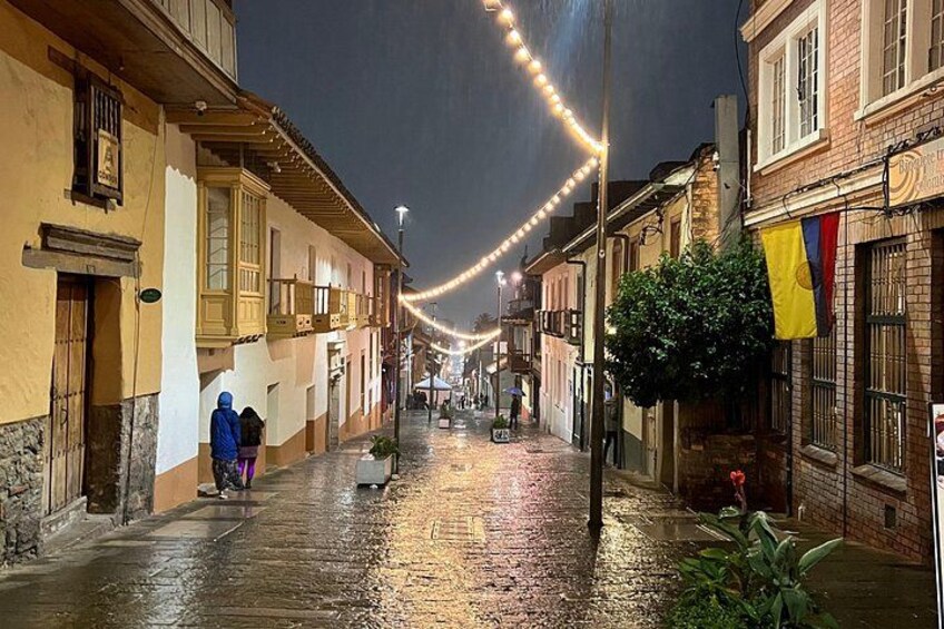 A wet cobblestone street at night with string lights overhead and buildings on either side. 4
