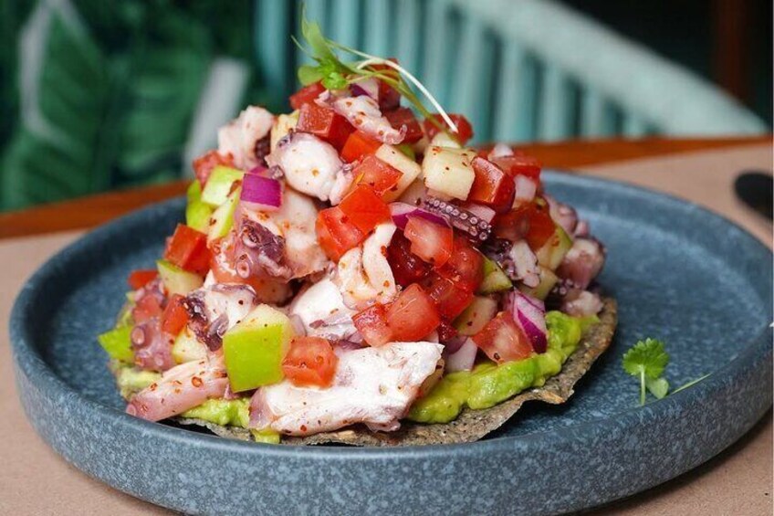 Ensalada de mariscos en un plato con aguacate, tomates y pulpo. 3