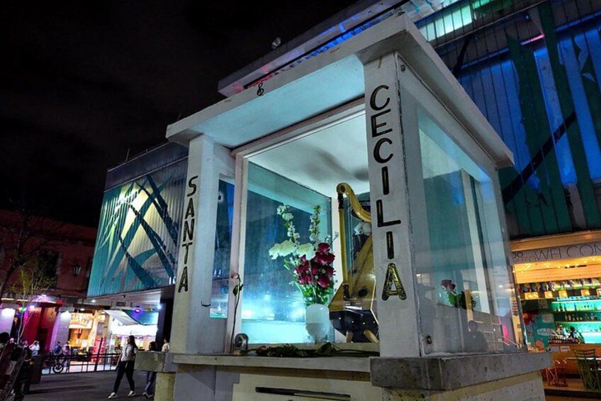 Una vivace strada cittadina di notte, con una bancarella ben illuminata che riporta il nome 'CECILIA'. 1