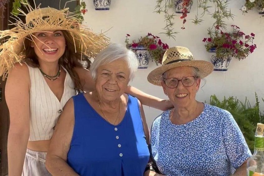 Three people standing outdoors with a wall of potted plants in the background. 1