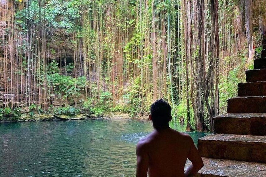 A person standing by a river with dense greenery and a staircase leading down. 2