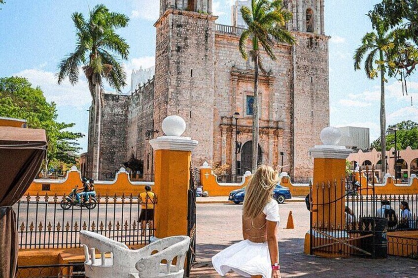 A historic building with a bell tower, palm trees, and a gated entrance. 5
