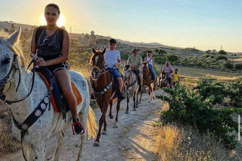 Un grupo de personas montando a caballo por un sendero de tierra, con un paisaje montañoso al fondo. 5
