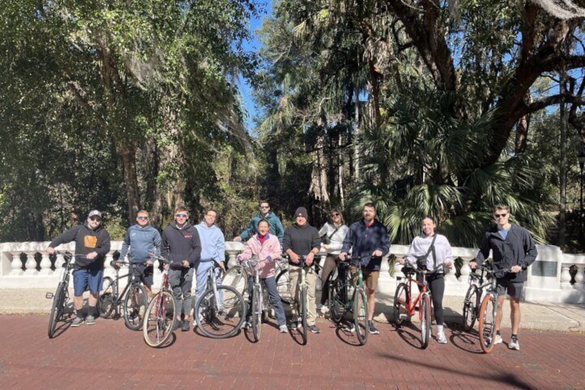 A group of people on bicycles in a park with trees and a paved walkway. 3