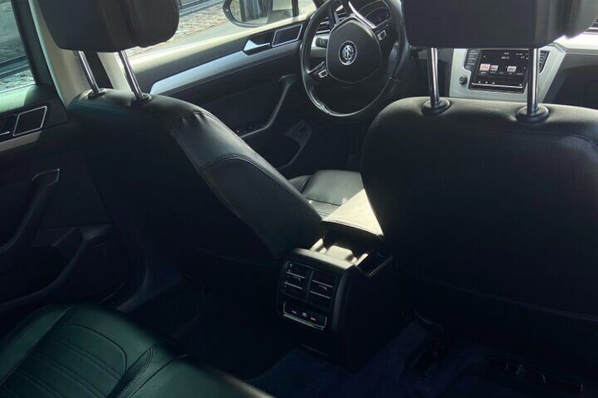 Een auto interieur met leren stoelen, een stuurwiel en een middenconsole met bedieningselementen. 2