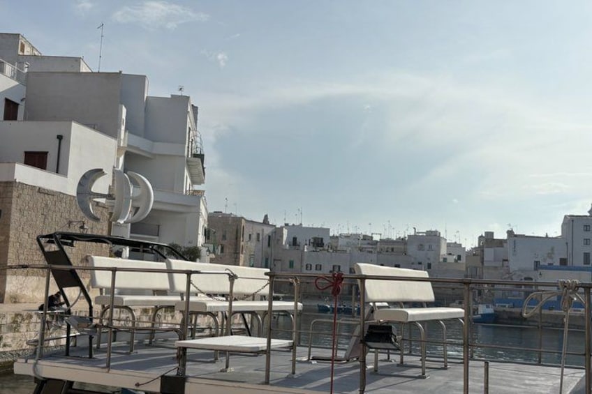 A waterfront with boats, a dock, and buildings in the background. 2