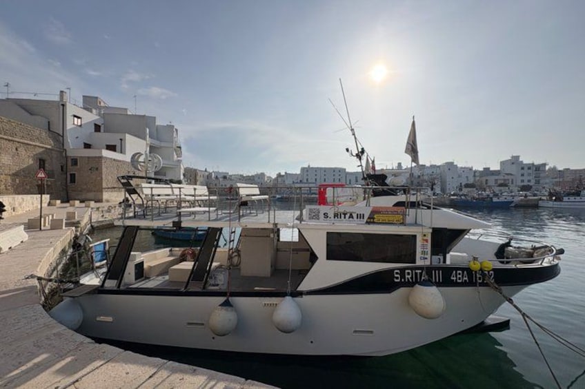 A boat named S.Rita III docked at a marina with buildings in the background. 3