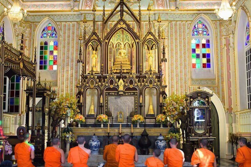 Interno di una chiesa decorata, con un altare centrale, vetrate colorate e monaci con abiti arancioni. 1