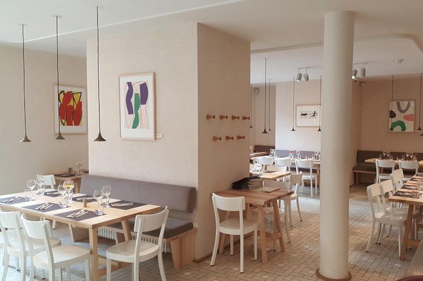 A restaurant interior with white chairs, tables, and hanging pendant lights. 2