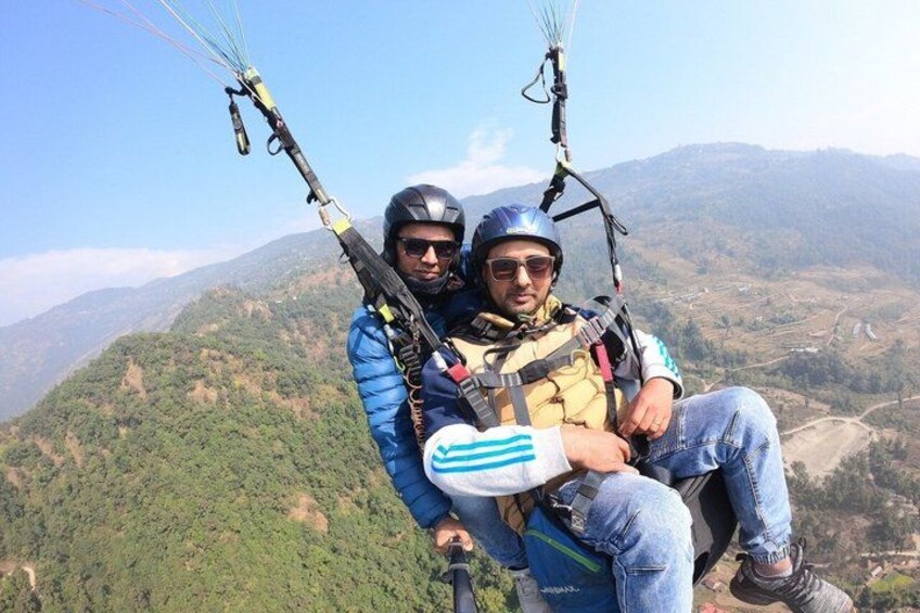 Two people paragliding over a mountainous landscape. 1