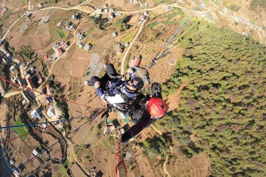 A person paragliding over a rural landscape with fields and scattered houses. 2