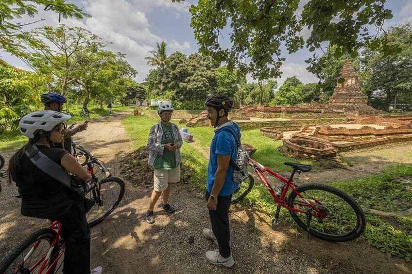 Tre persone con biciclette, una mountain bike rossa e un antico tempio sullo sfondo. 4