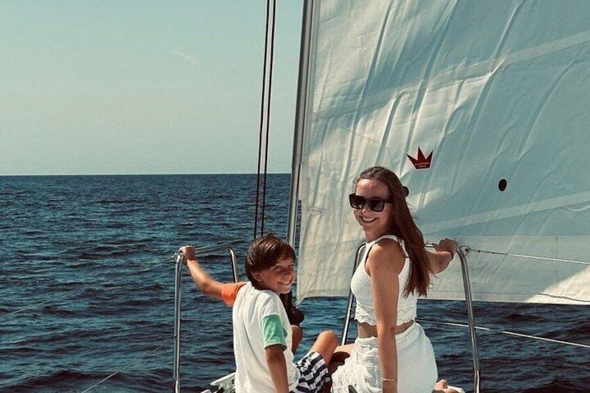 A sailboat on the water with a person holding onto the sail. 4