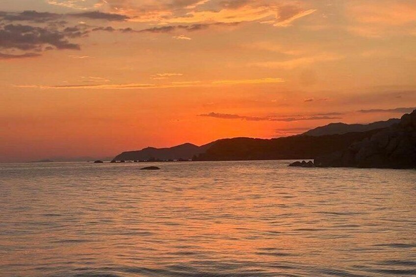 A sunset over a calm sea with distant landforms. 5