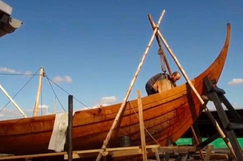 A wooden boat under construction with a person working on it. 3