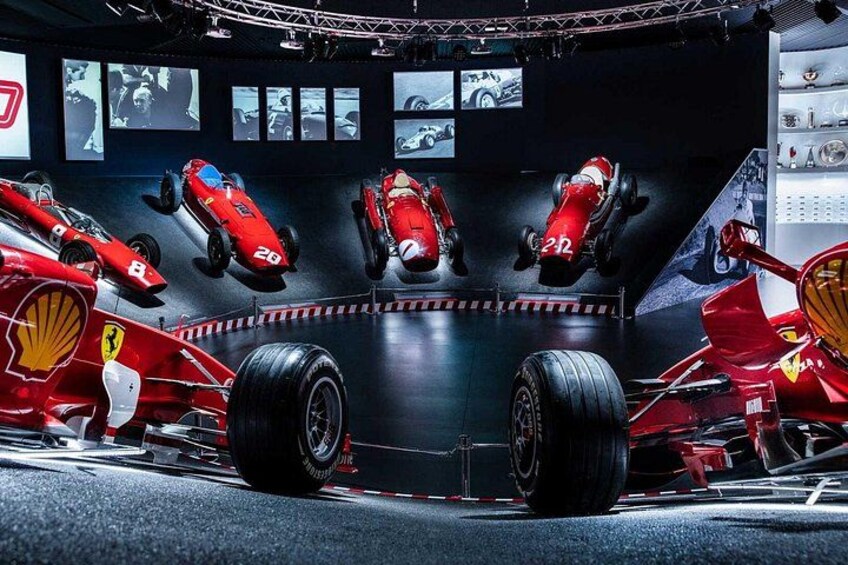 A racing car in a museum display with other cars and racing memorabilia. 2