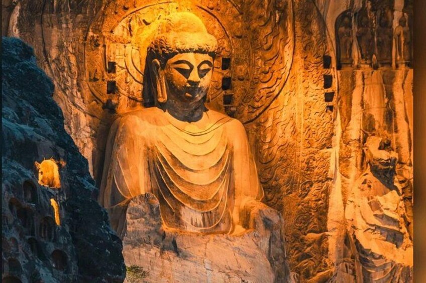Una gran estatua de Buda en una cueva con tallas intrincadas y un halo. 1
