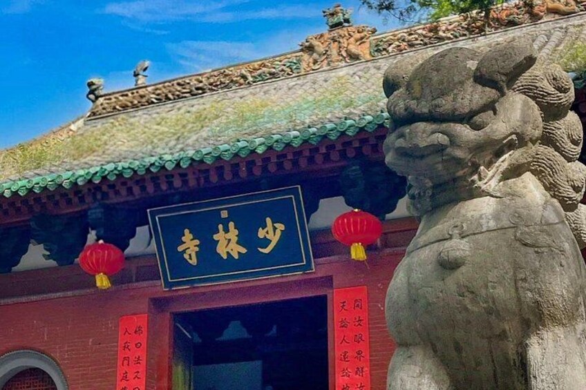 Un edificio tradicional chino con una estatua de león, un letrero y faroles rojos. 2