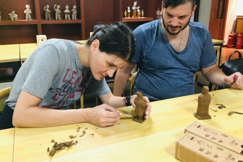 Due persone lavorano a sculture in argilla a un tavolo. 1