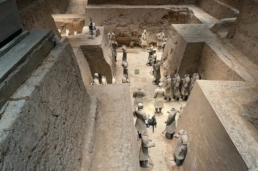 Un sito di scavi archeologici con figure in terracotta e operai. 3