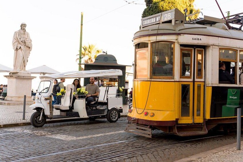 A tram with passengers, a statue, and a tram stop. 1