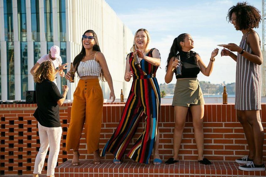 A group of people on a rooftop terrace with a modern building in the background. 3