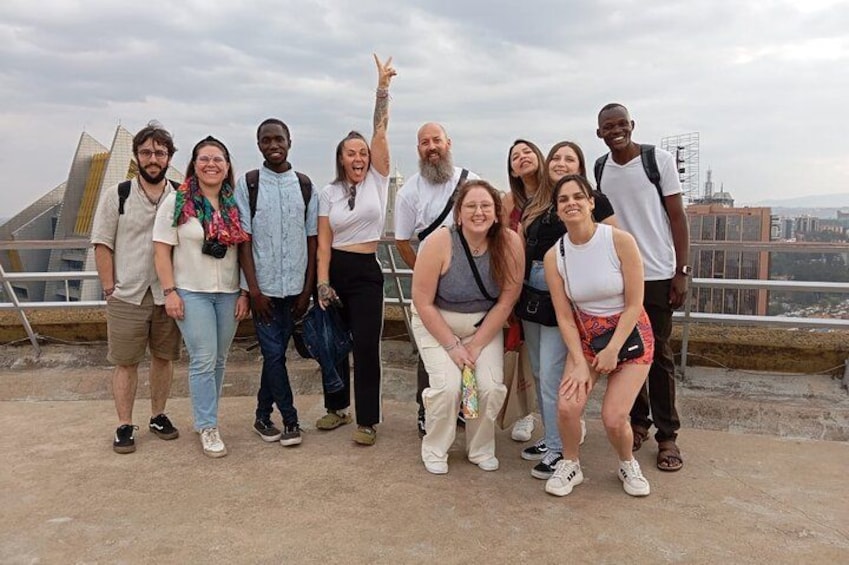 A group of people posing on a concrete platform with a pyramid structure in the background. 1
