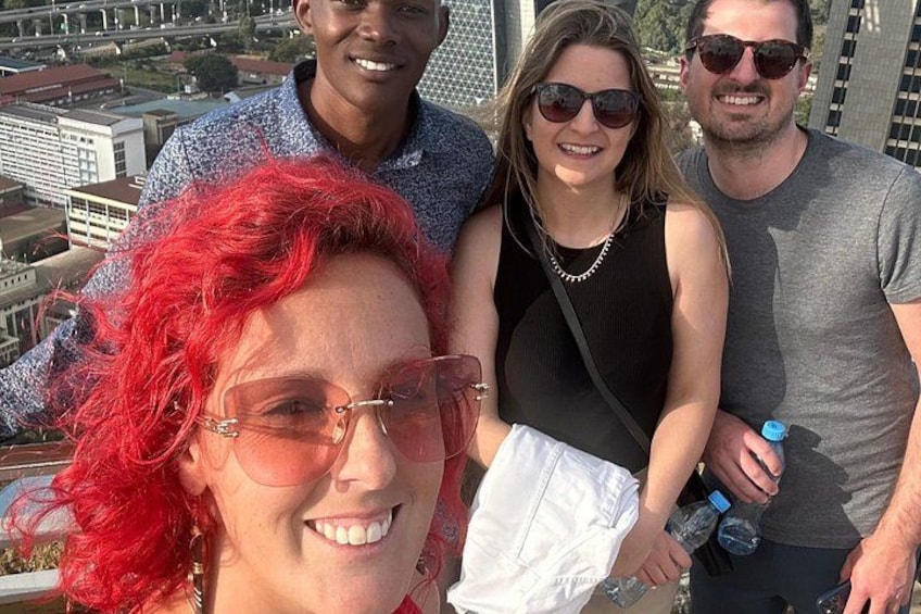 A group of people standing on a rooftop with a cityscape in the background. 2