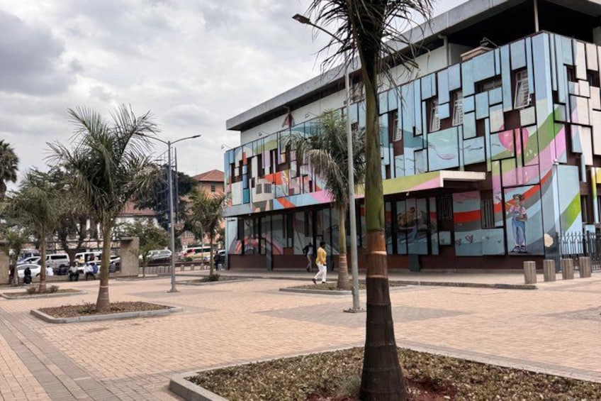 A modern building with colorful geometric patterns, palm trees, and a paved walkway. 4