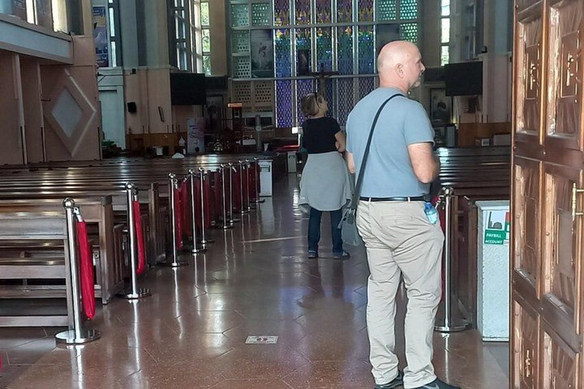 A church interior with pews, a man standing, and a woman walking. 3